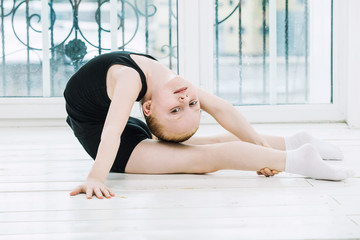 Little Child Girl gymnast doing stretching in a bright room on a happy and cute window background