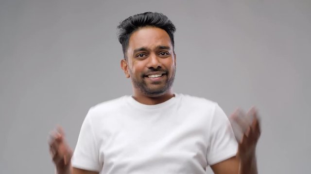 people, emotion and expression concept - confused indian man shrugging shoulders over grey background