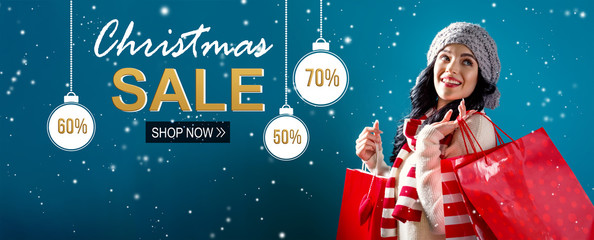Christmas sale message with young woman holding shopping bags
