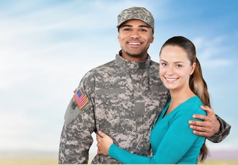 Smiling soldier with his wife standing against  background