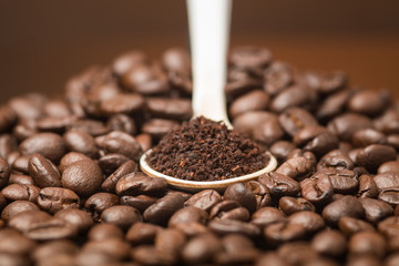 Topview Coffee powder in the white Spoon over the coffe beans