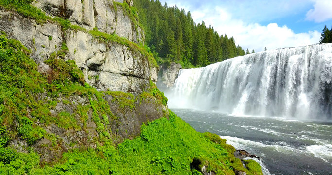 Mesa Falls, Idaho, USA - Wide Waterfalls Surrounded By Green Pine Trees With A Rainbow