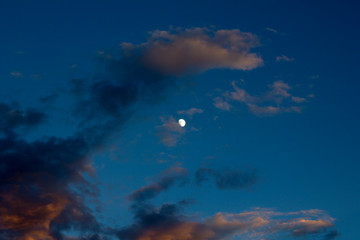 dark blue sky of late sunset with moon and multi-colored clouds