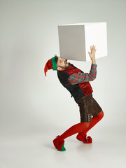 The happy smiling friendly man dressed like a funny gnome or elf posing on an isolated gray studio...