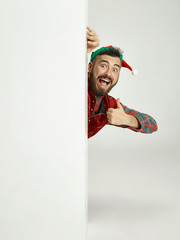 The happy smiling friendly man dressed like a funny gnome or elf posing on an isolated gray studio...