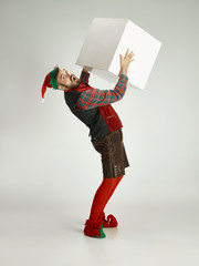 The happy smiling friendly man dressed like a funny gnome or elf posing on an isolated gray studio...