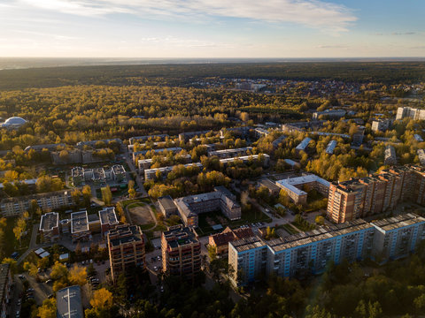 Aerial view of a large number of big and small houses on the outskirts of the city on an autumn afternoon during Indian summer with the road and cars