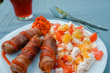 Chevapchichi. Meat sausages with vegetable salad, ketchup and adjika on white plate. Dish of Balkan cuisine.