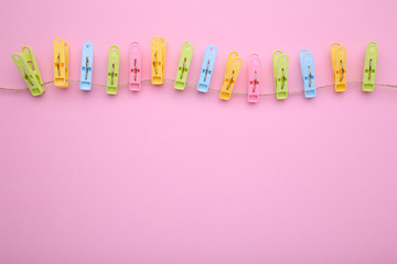 Colorful clothes pins on rope on pink
