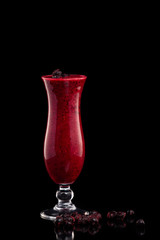 Glass of red currant fresh shake decorated with currant berries isolated at black background.