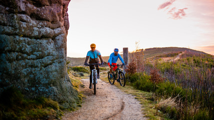 Fototapeta premium Cycling woman and man at Beskidy mountains forest landscape. Couple riding MTB enduro track. Outdoor sport activity.