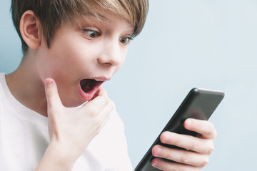Fototapeta premium Boy looks at phone in surprise