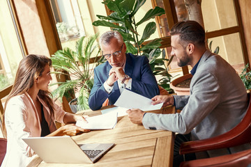 Business lunch. Three people in the restaurant sitting at table discussing project joyful. Team work concept