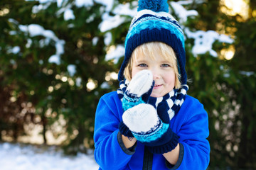 Funny little boy has fun with snowglobe im winter forest
