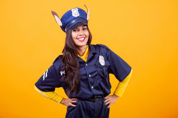 Beautiful young woman wearing Police costume over yellow background. Having fun.