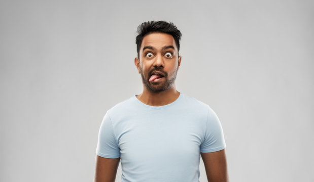 expression, rudeness and people concept - indian man making faces and showing his tongue over gray background