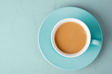 Coffee with milk in a turquoise cup on the table. View from above. Close-up.