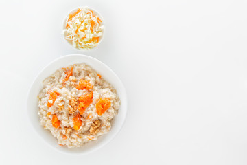 Fototapeta na wymiar Oatmeal with pumpkin and nuts, cabbage and carrot salad on a white background. View from above. Copy space.