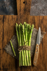 A bunch of fresh asparagus on a cutting board with a knife. Top view, flat lay.