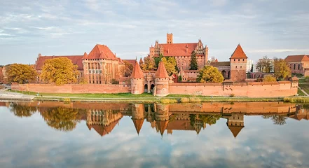 Wall murals Castle Malbork castle autumn panorama with reflection, at sunset