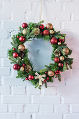 Christmas wreath hanging on white brick wall