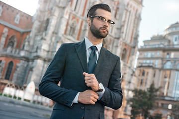 Close up profile portrait of a successful young bearded guy in suit and glasses. So stylish and...