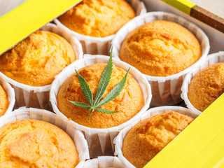 Freshly baked cinnamon mini muffins with cannabis and buds of marijuana on the table. Concept of cooking with cannabis herb. Treatment of medical marijuana for use in food.