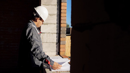 Man with paper draft in building under construction