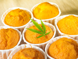 Freshly baked cinnamon mini muffins with cannabis and buds of marijuana on the table. Concept of cooking with cannabis herb. Treatment of medical marijuana for use in food.