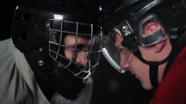 Concept confrontation hockey players. Close-up of a goalkeeper and a forward head-on, helmet-to-helmet. The rage and hatred on the ice field.