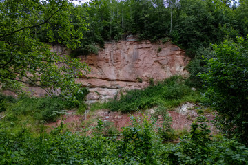 rocky stream of river deep in forest in summer green weather with sandstone cliffs
