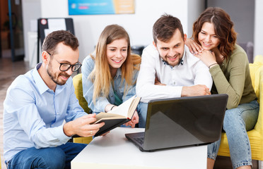 Young people friendly discussing while sitting with laptop in common hall of hostel