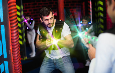 Emotional guy playing laser tag in colorful beams