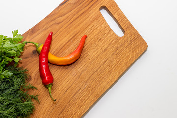 Fresh chili pepper, parsley and dill on board, closeup.wooden board with vegetables and condiments isolated on white background.Copy space