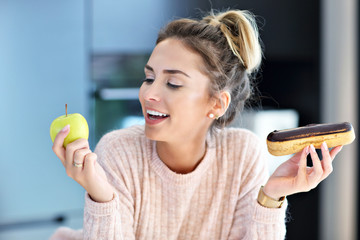 Woman choosing between apple and eclair