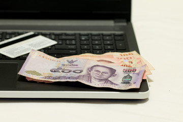 A blurred of  credit card, Thai currency 500 Baht and laptop after shopping on line, E-commerce net work marketing concept