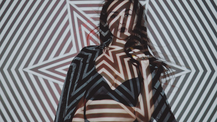 Portrait of woman in lingerie and jacket posing with projected pattern on her. Music, nightclubs, shows and entertainment concept