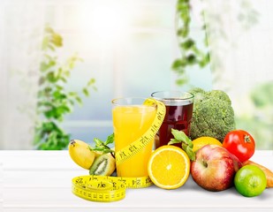 Glasses of fresh juice and fruits with vegetables and measuring