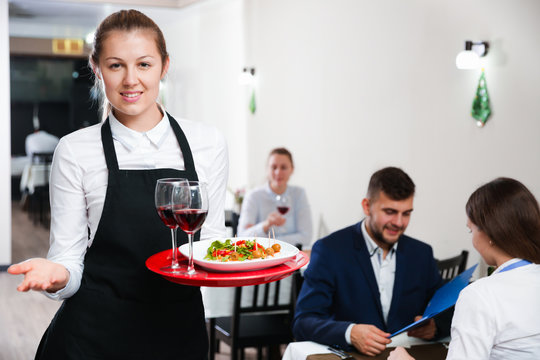 Portrait of woman waiter who is standing with dish in restaurante