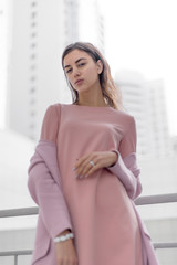 portrait of a young beautiful brunette woman on the street, female urban street fashion, lines of buildings