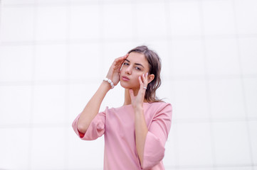 portrait of a young beautiful brunette woman on the street, female urban street fashion, lines of buildings