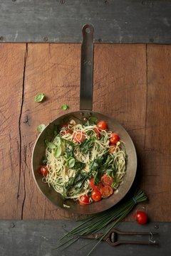 Pan of capellini with spinach, cocktail tomatoes and herbs