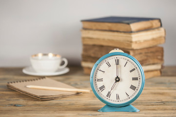 stack of books and alarm clock on it on wooden table.