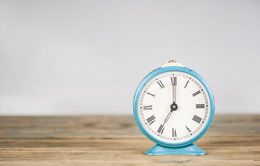 vintage alarm clock on wooden table over white background