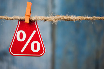 Sale tags with sign percent hanging from brown rope over wooden wall. Happy New Year sale concept