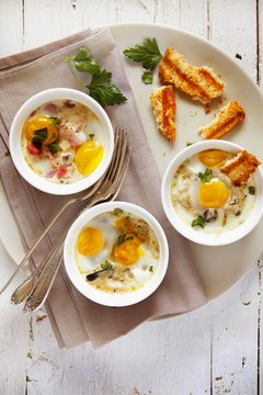 Quail eggs, bacon and mushroom cocotte served in bowl on plate