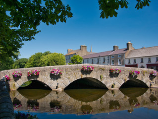 Alte Brücke mit Blumen spiegelt sich im Wasser