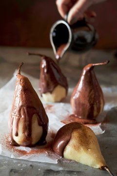 Liquid chocolate being poured over poached cinnamon pears