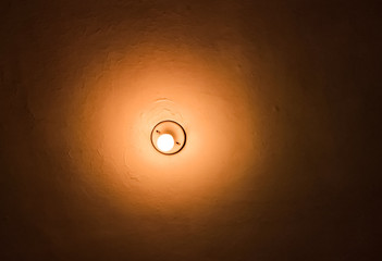 Light bulb in the ceiling. Concept of idea or light in the dark. Orange texture and background with light tones.