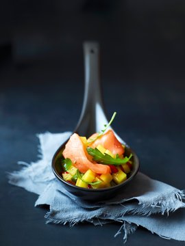 Close Up Of Spoon With Raw Salmon And Mango Salsa